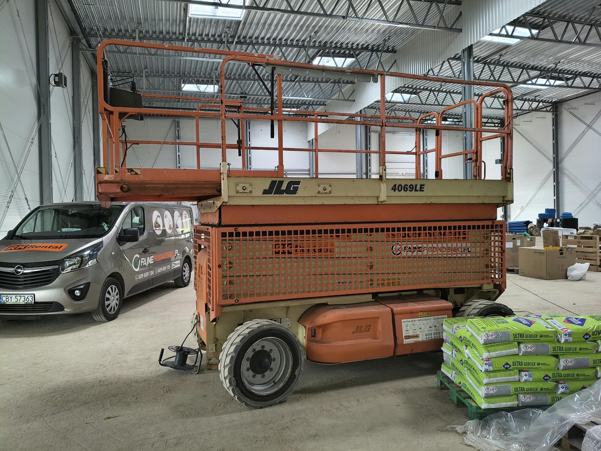 RK Rental mobile service: maintenance inspection of a JLG 4069LE electric scissor lift at a customer's warehouse hall