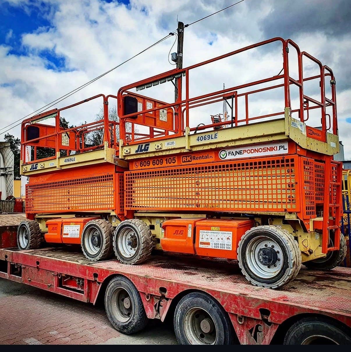Two JLG 4069LE scissor lifts on an RK Rental low-loader trailer during transport