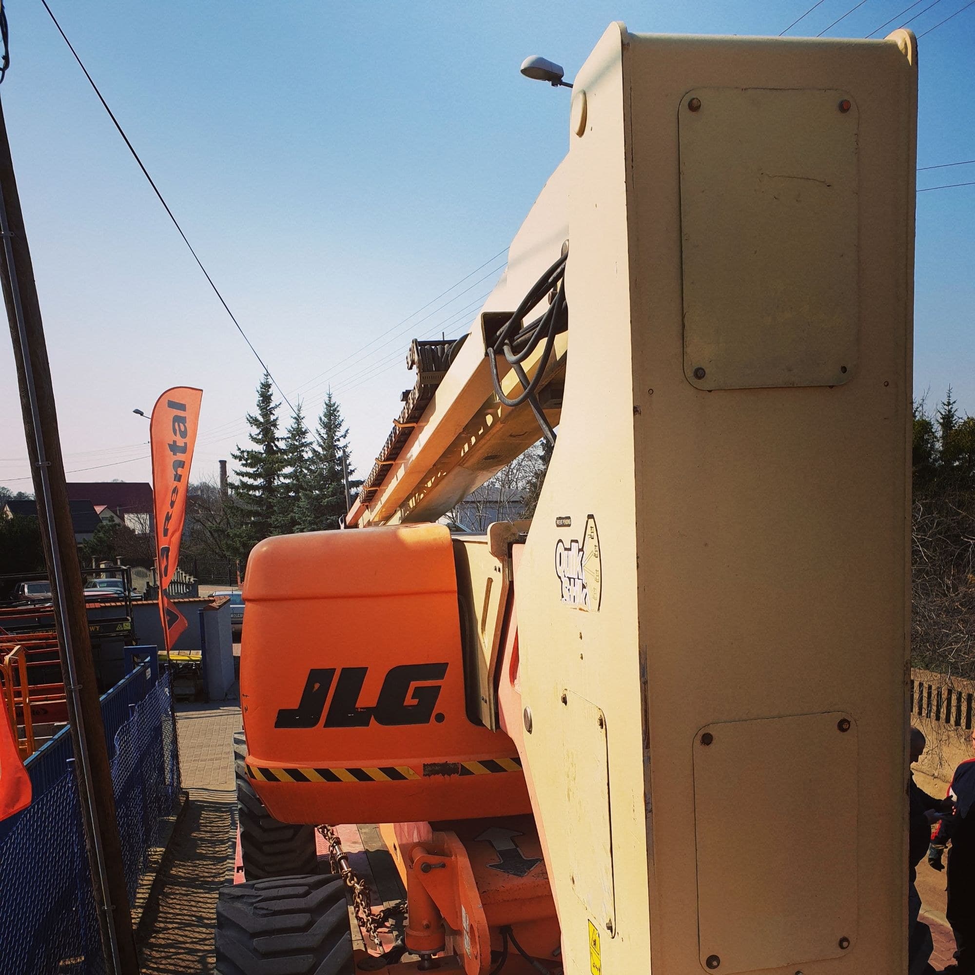 JLG 800AJ rough terrain articulating boom lift (26 m, 4×4) from RK Rental secured with transport chains on a trailer, delivery to Wągrowiec