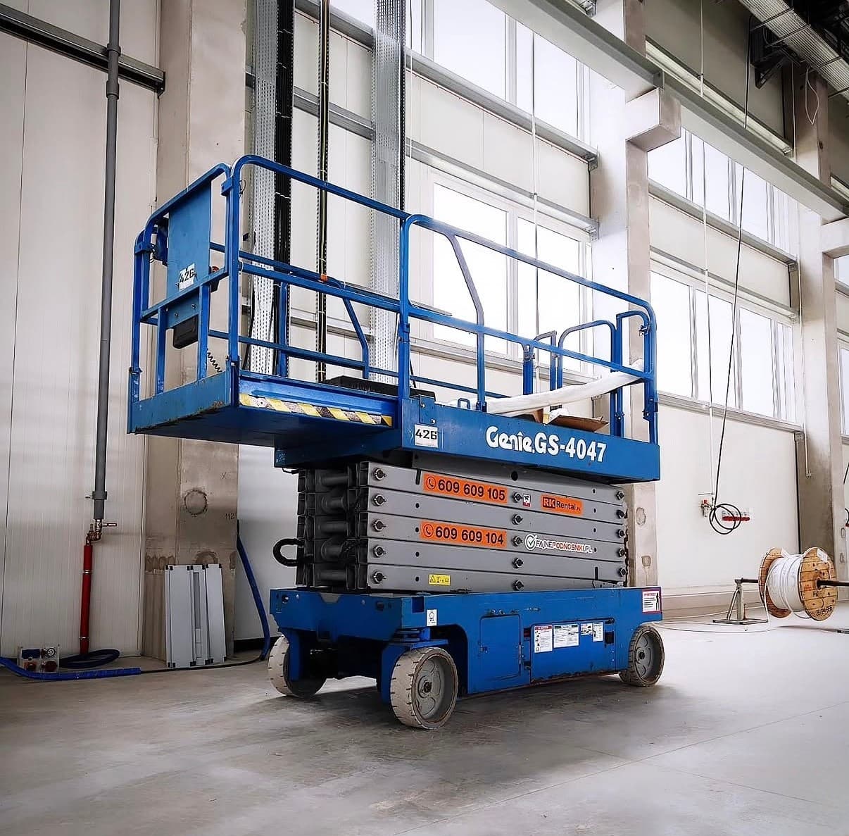 Podnośnik nożycowy elektryczny Genie GS-4047 (14 m) RK Rental w hali produkcyjnej w Szczecinku podczas prac utrzymania ruchu