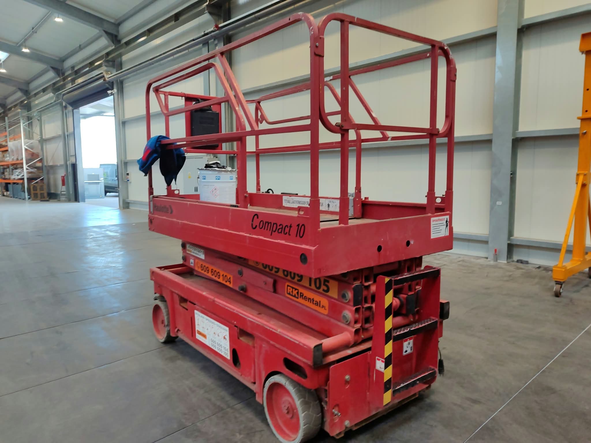 Haulotte Compact 10 electric scissor lift (10 m) from RK Rental in a warehouse in Chełmża