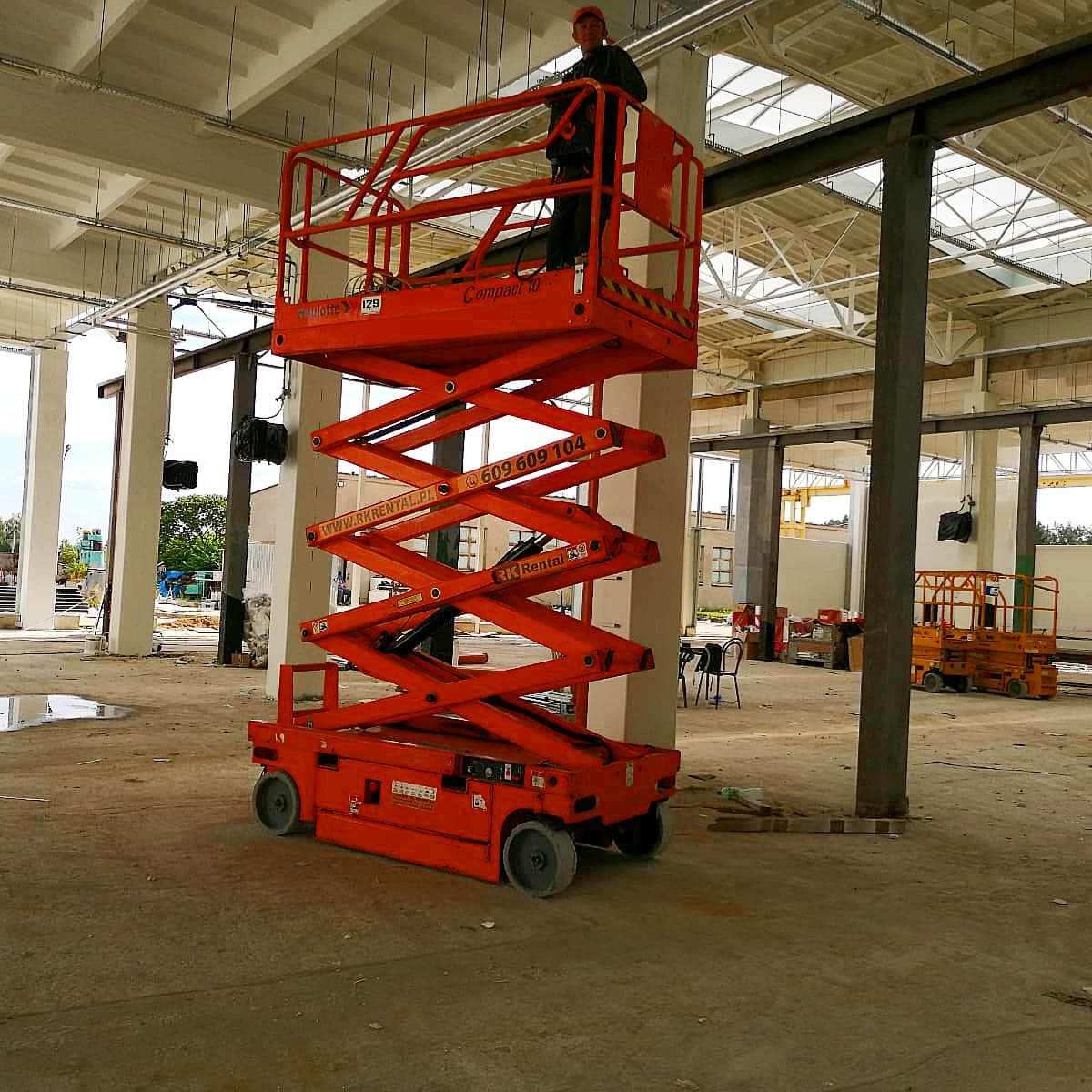 Podnośnik nożycowy elektryczny Haulotte Compact 10 (10 m) RK Rental podczas remontu hali produkcyjnej w Poznaniu