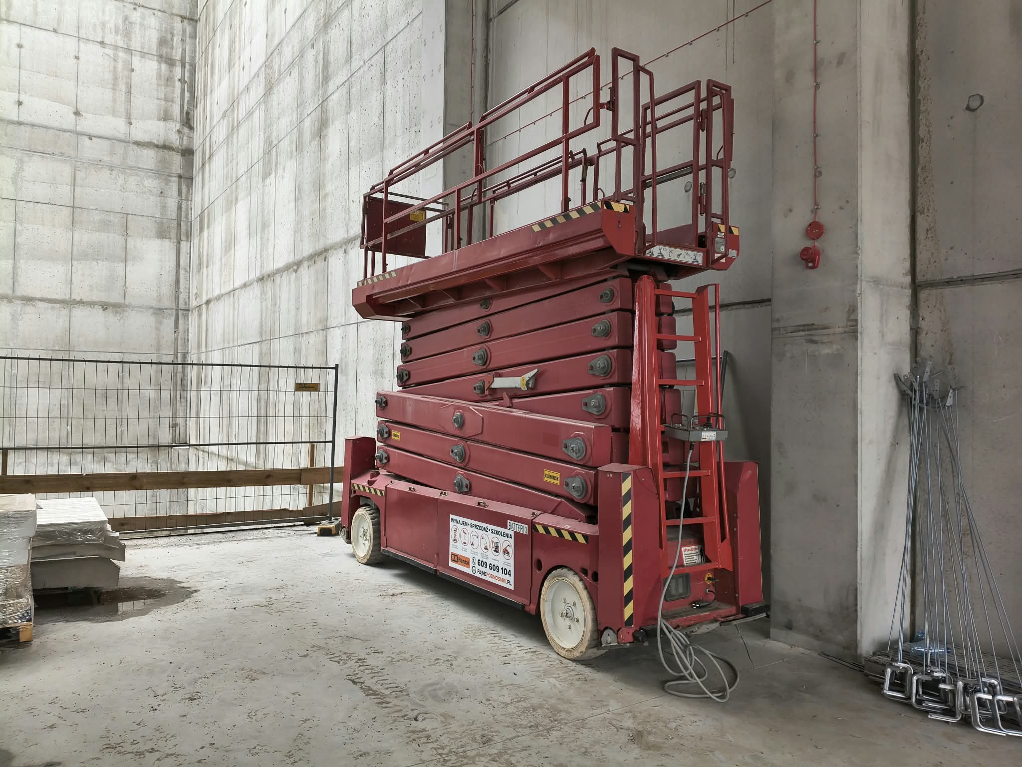 PB Lifttechnik S225-12ES electric scissor lift (22.5 m) from RK Rental in a warehouse with concrete walls under construction in Wrocław