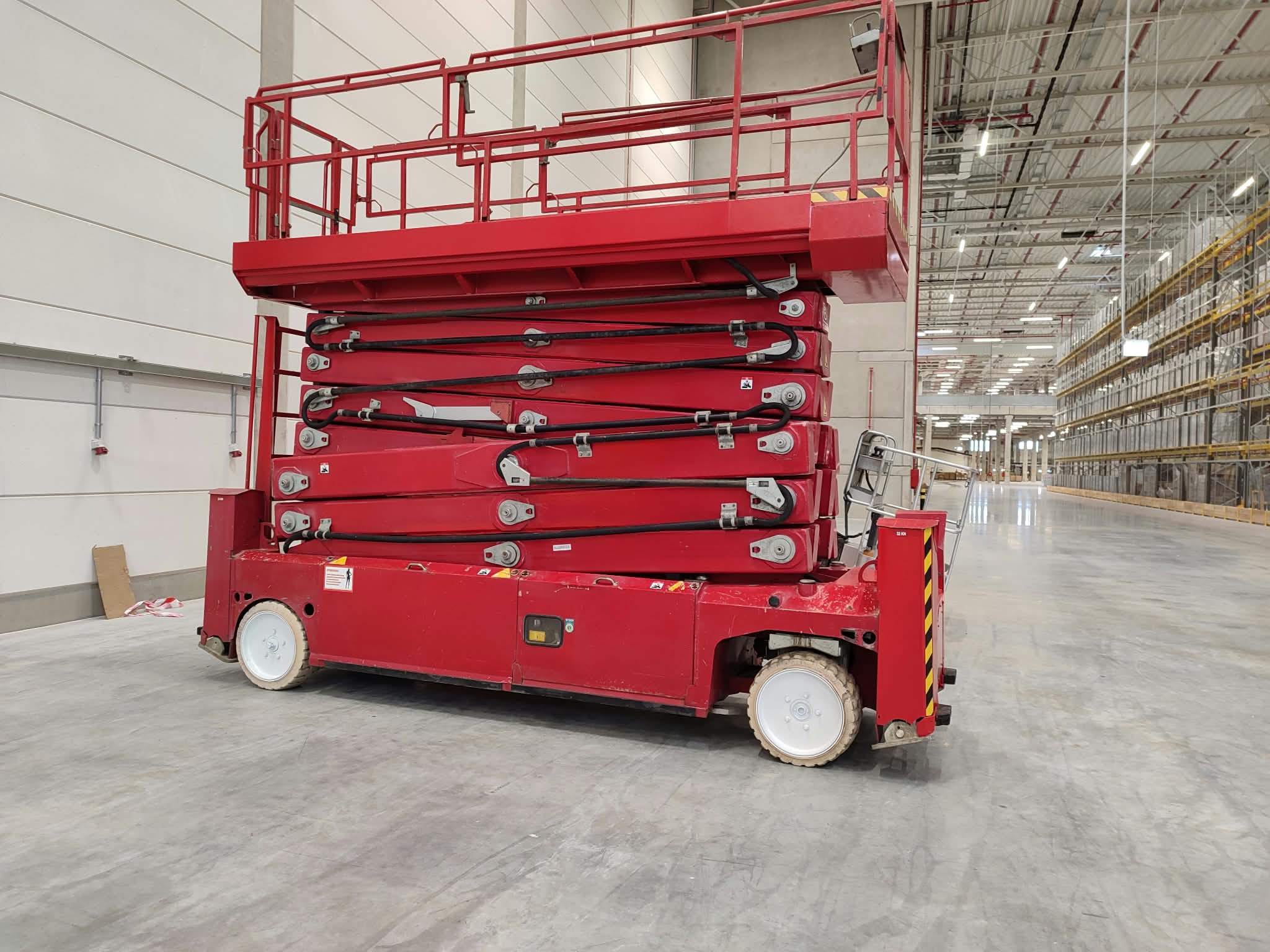 PB Lifttechnik S225-12ES electric scissor lift (22.5 m) from RK Rental in a logistics centre in Łódź with high-bay racking
