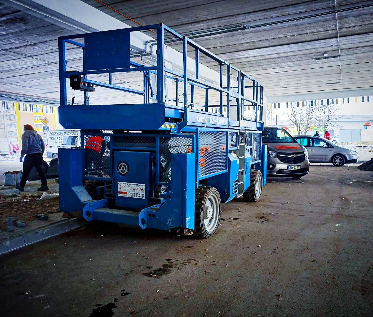 Podnośnik nożycowy terenowy Genie GS-4390 (15 m) RK Rental podczas prac w hali w Poznaniu
