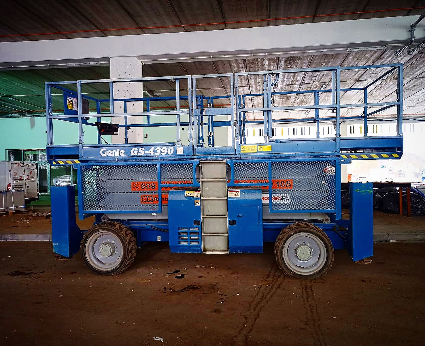 Terenowy podnośnik nożycowy Genie GS-4390 (15 m, 4×4) RK Rental podczas prac w hali w Poznaniu
