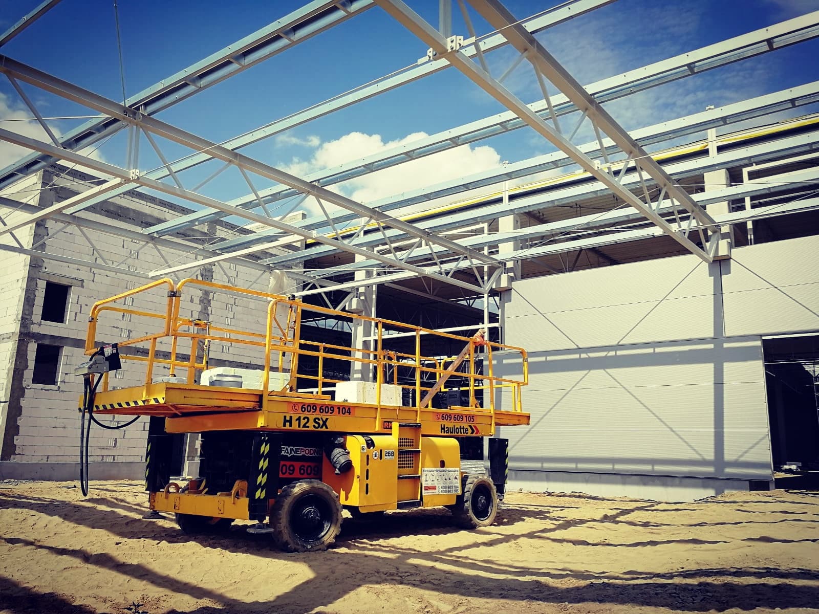 Podnośnik nożycowy terenowy Haulotte H12SX (12 m) RK Rental przy budowie hali magazynowej w Solcu Kujawskim