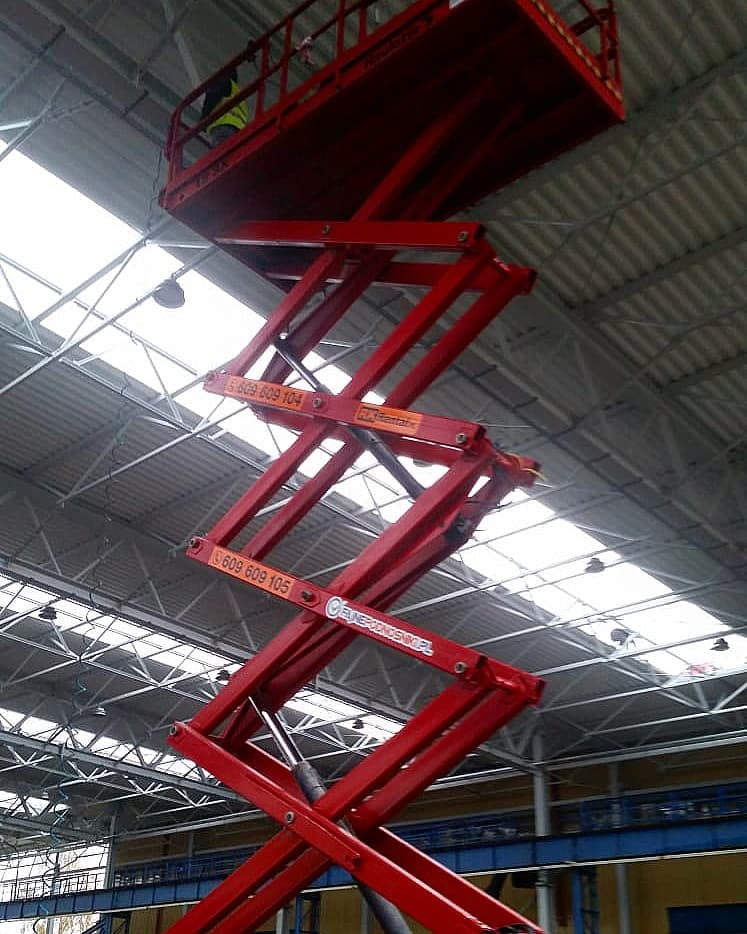 RK Rental rough terrain scissor lift during the installation of services under the roof of a hall in Włocławek
