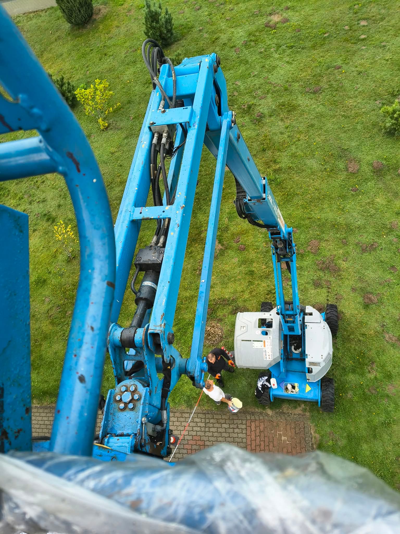 Wynajęty podnośnik przegubowy spalinowy Genie Z-45 (16 m, 4×4) RK Rental podczas konserwacji elewacji budynku w Chojnicach