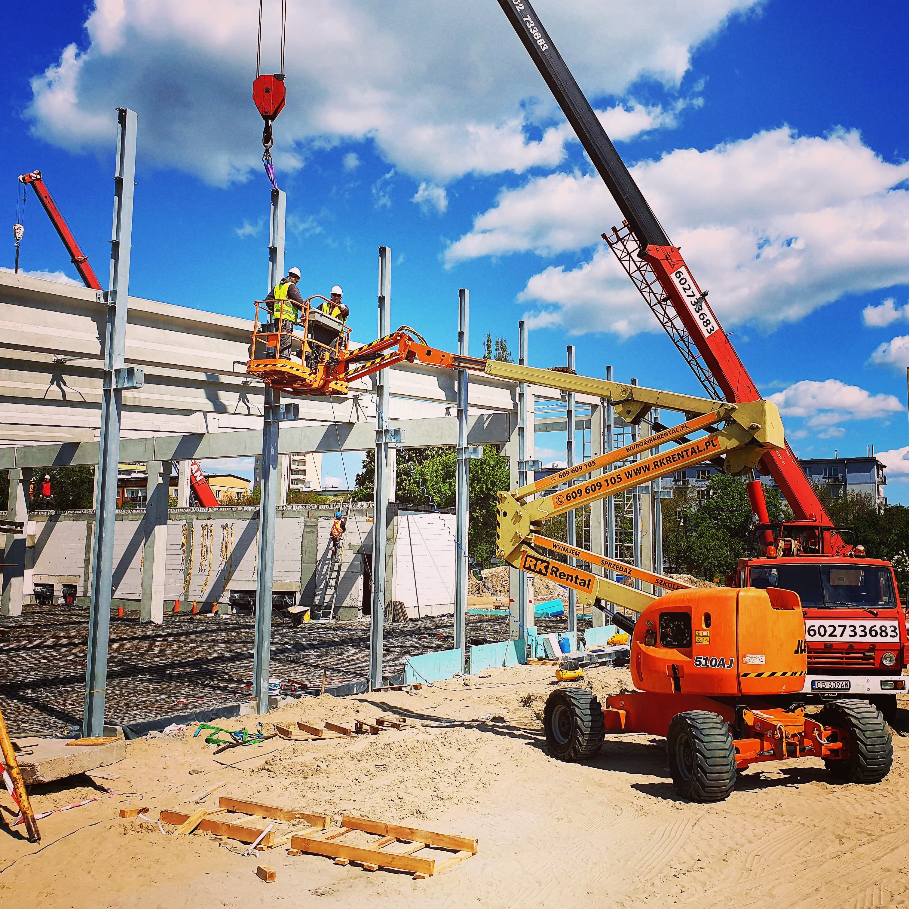 Rented JLG 510AJ diesel rough terrain articulating boom lift (18 m, 4×4) from RK Rental during steel structure erection with a crane in Włocławek