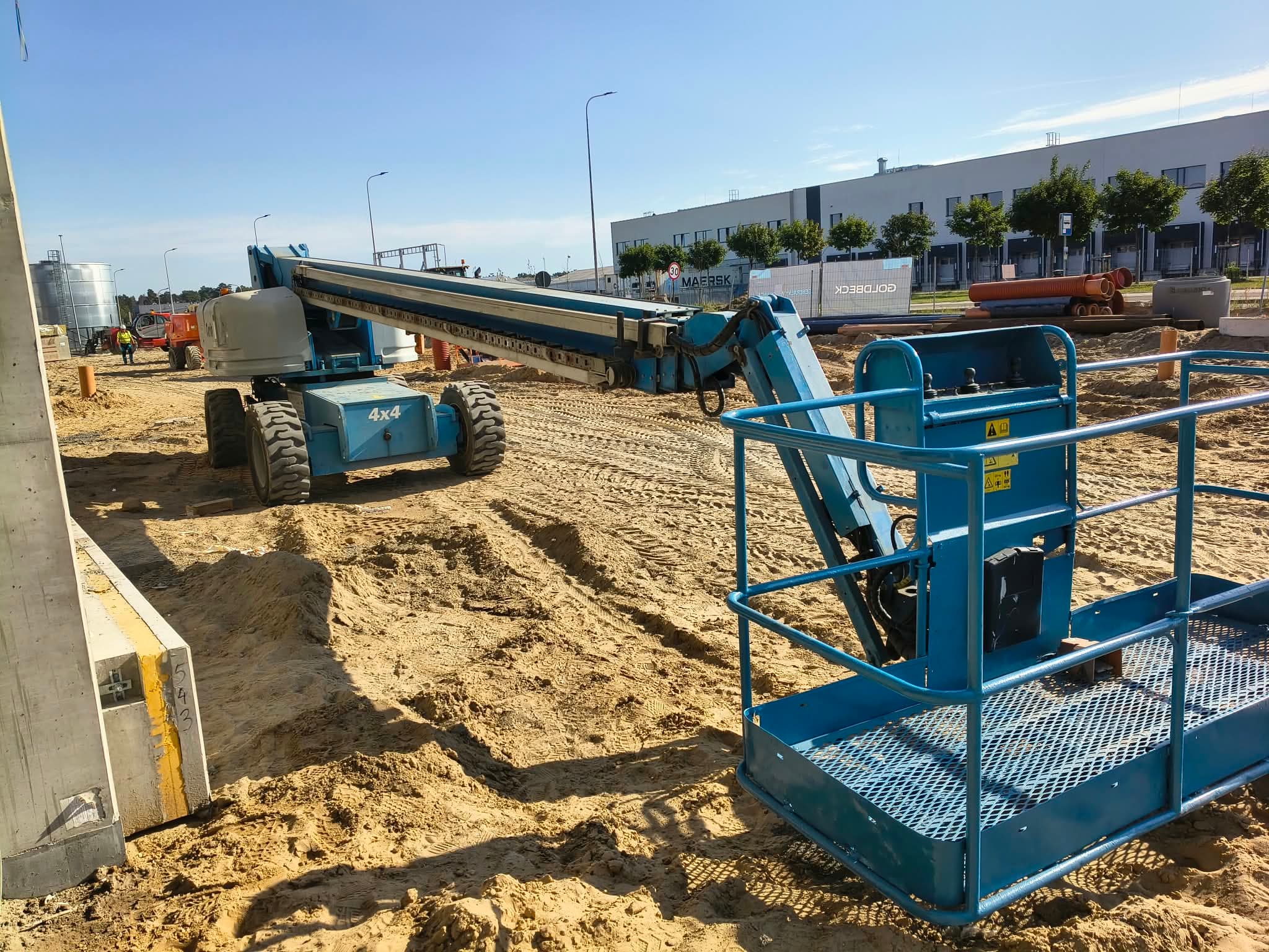 Terenowy podnośnik teleskopowy Genie S-85 (28 m, 4×4) RK Rental na piaszczystym placu budowy hali w Zielonej Górze