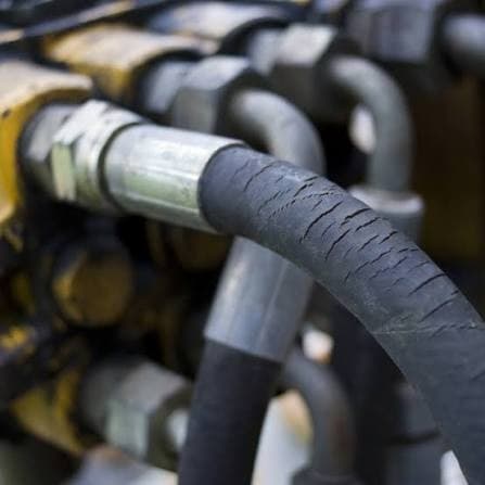 Crumbling cover of a hydraulic hose in a construction machine: transverse cracks in the rubber on the bend of the hose
